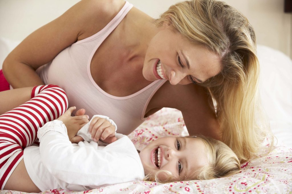 Mother And Daughter Relaxing Together In Bed