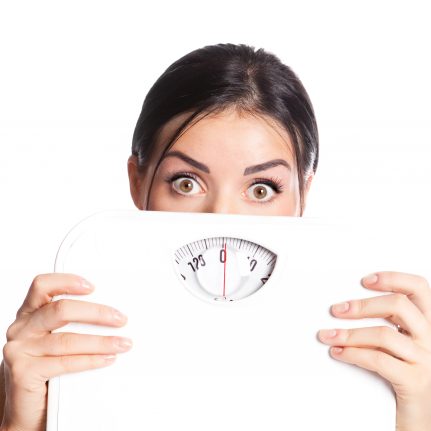 Woman holding scale looking scared