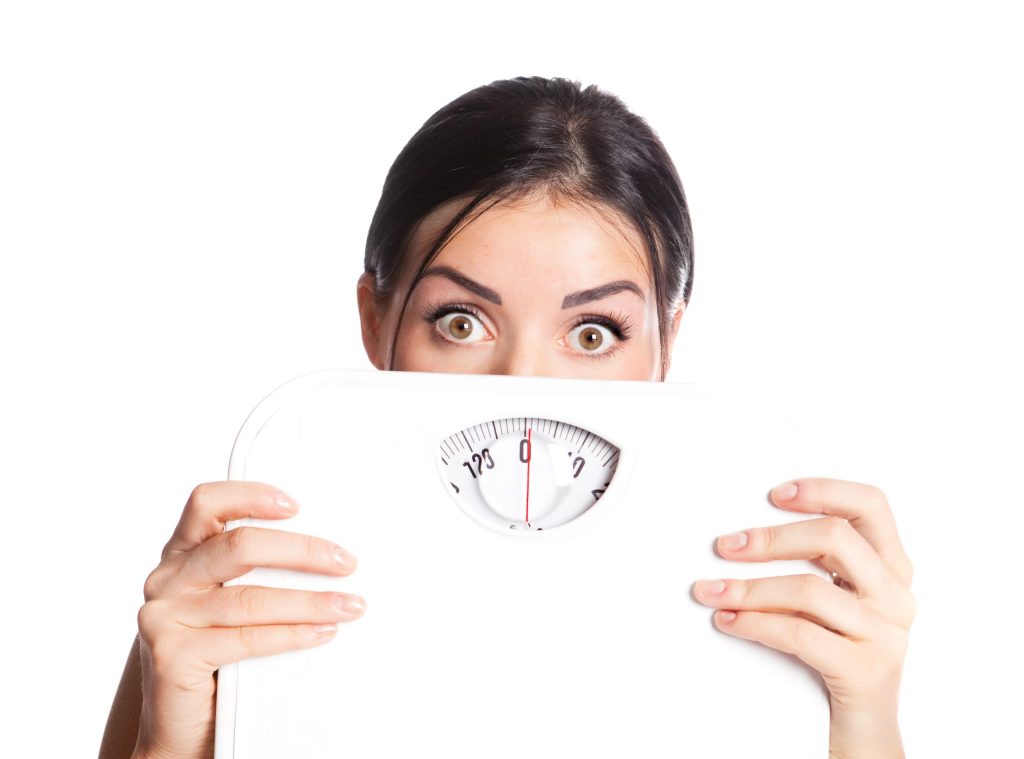 Woman holding scale looking scared