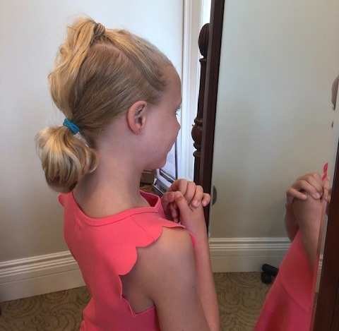 girl looking in mirror after ear piercing