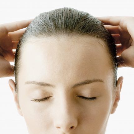 woman with eyes closed, hands on head