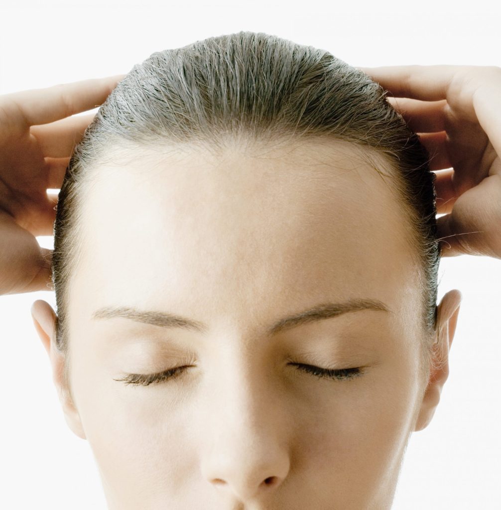 woman with eyes closed, hands on head