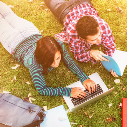 college students sitting on grass working on homework