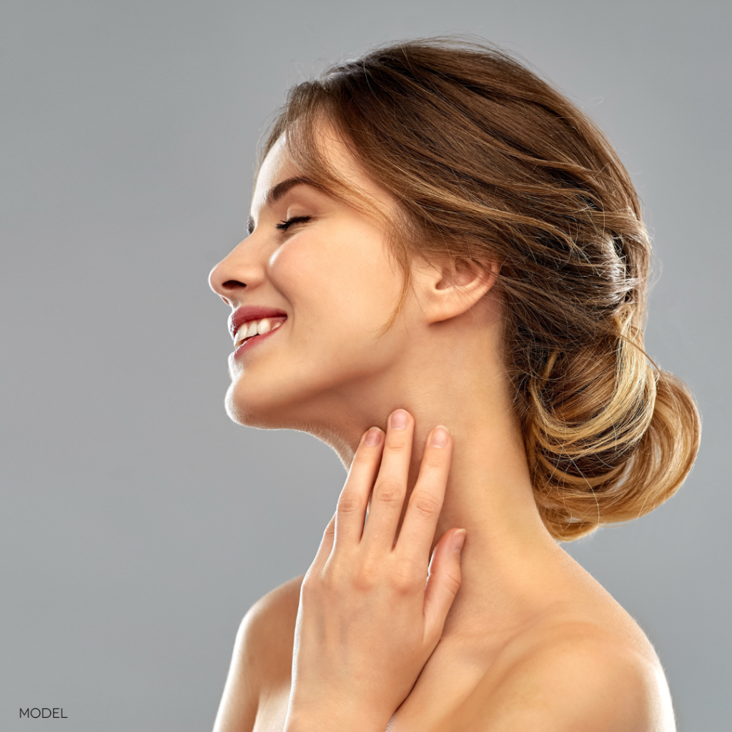 young woman with hair pulled back and hand on neck