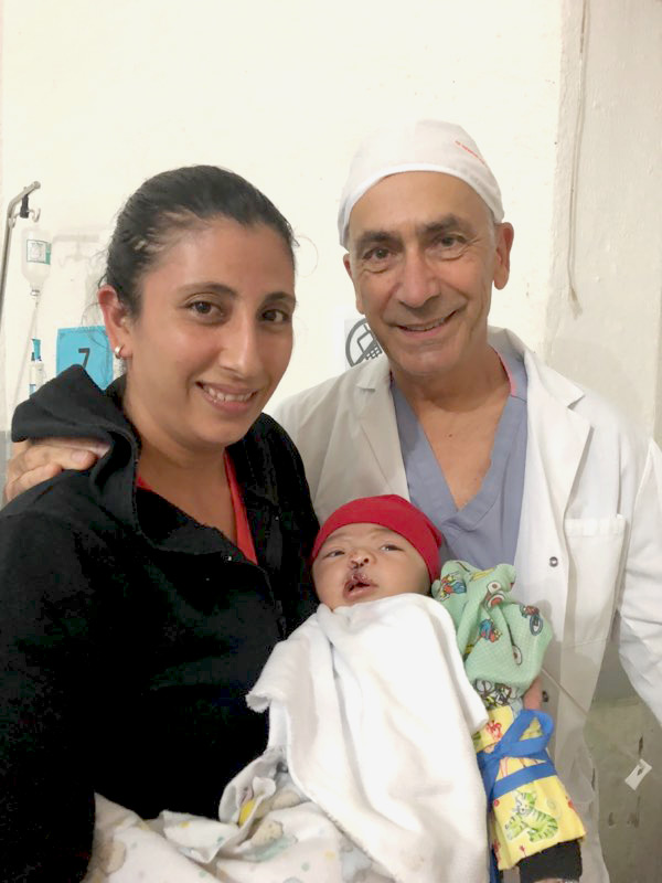 Dr. Koenig with a mother and child (patient) on a HUGS Foundation medical mission trip during which he performed pediatric cleft lip and palate surgeries.